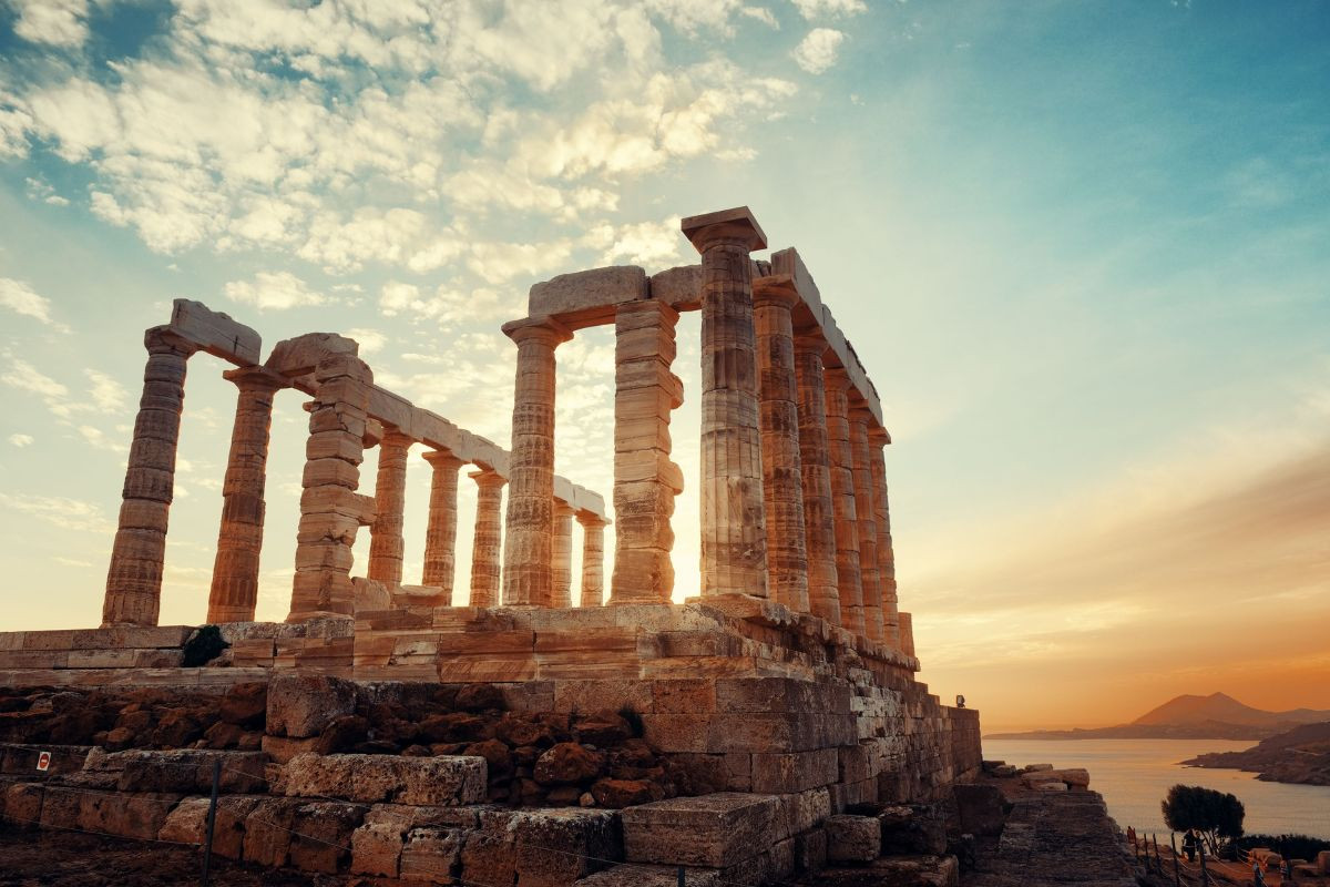 The Temple of Poseidon with towering columns against a warm sky near the sea.